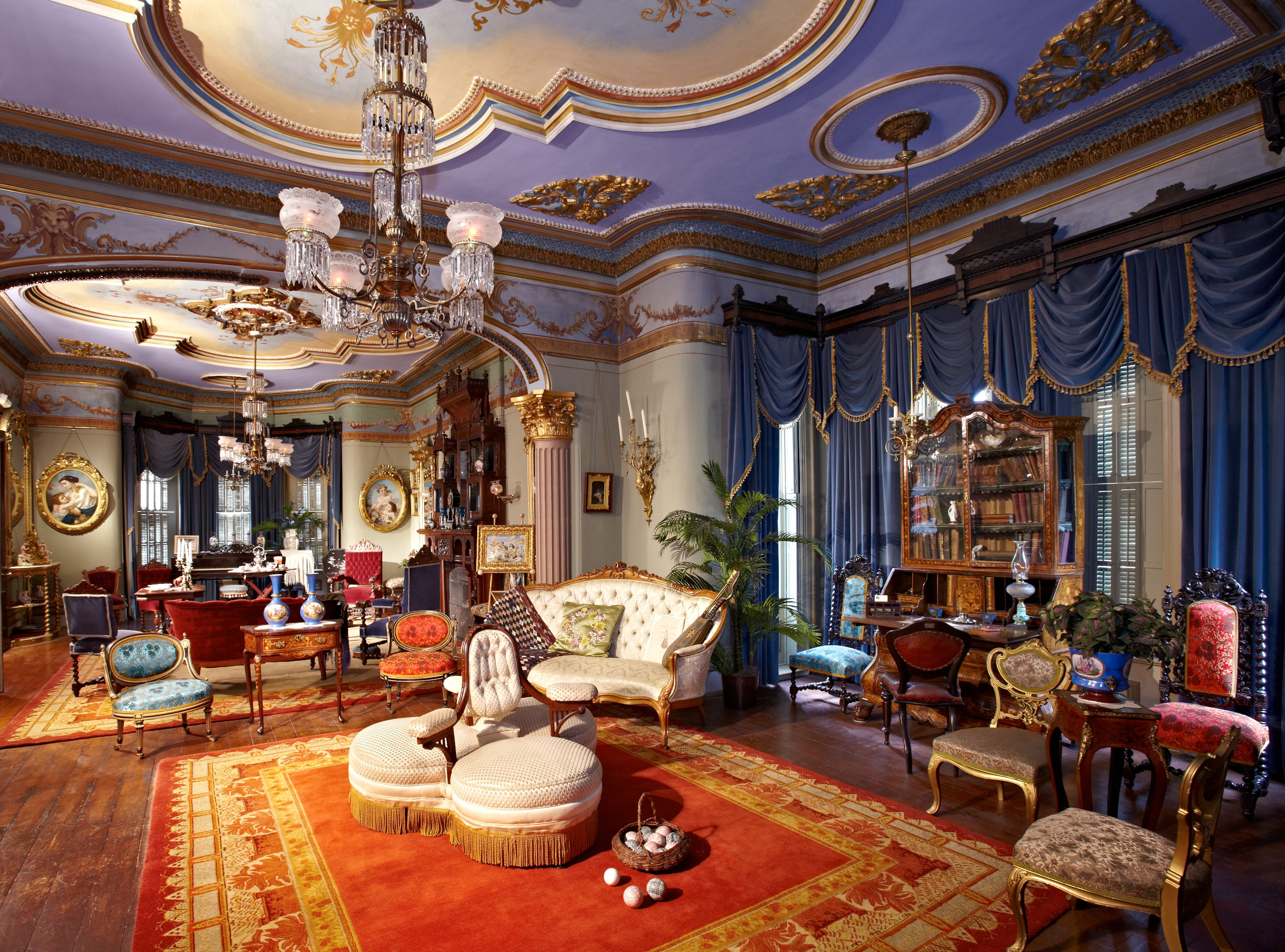 Glanmore's double drawing rooms features elaborate furnishings such as the white three seated chaperone's chair as well as elaborately painted ceilings featuring grotesque faces. 