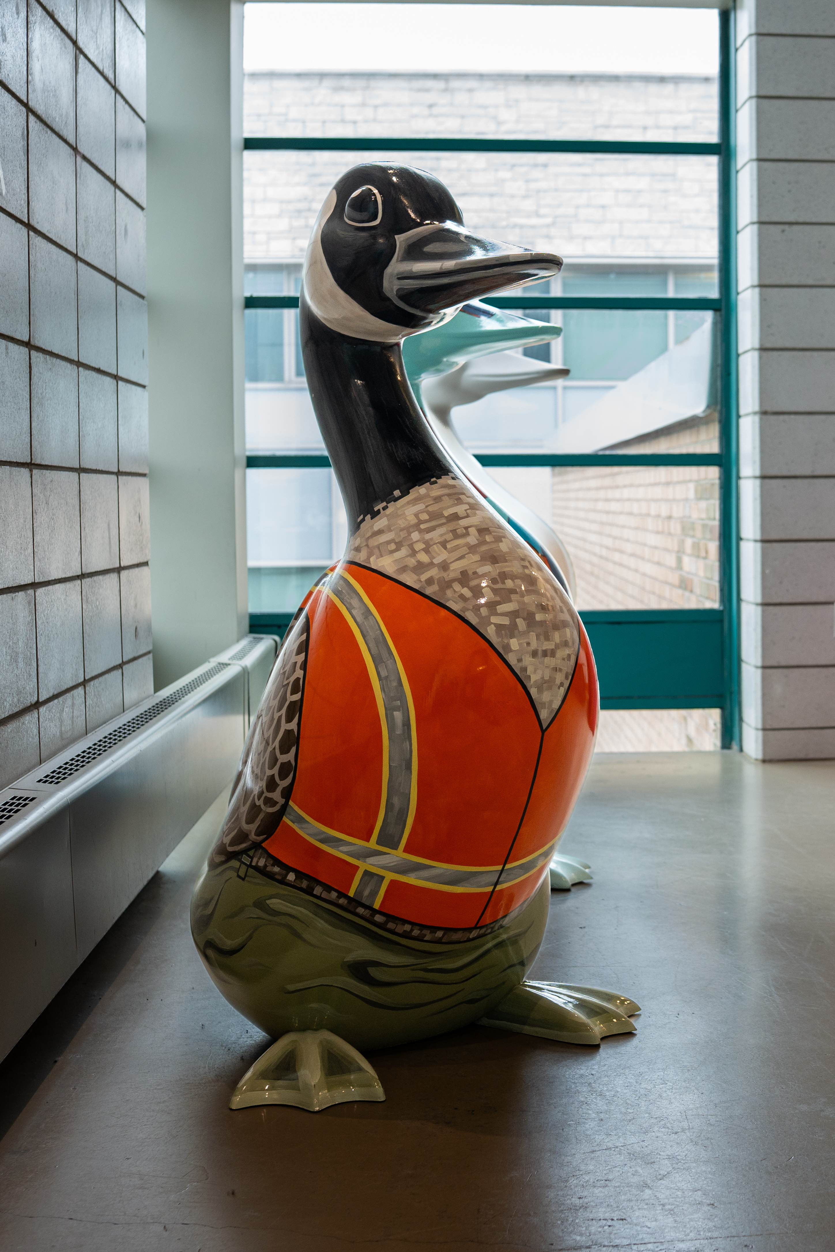 A 4.5-foot-tall fiberglass goose wearing an orange and yellow high-visibility construction vest.