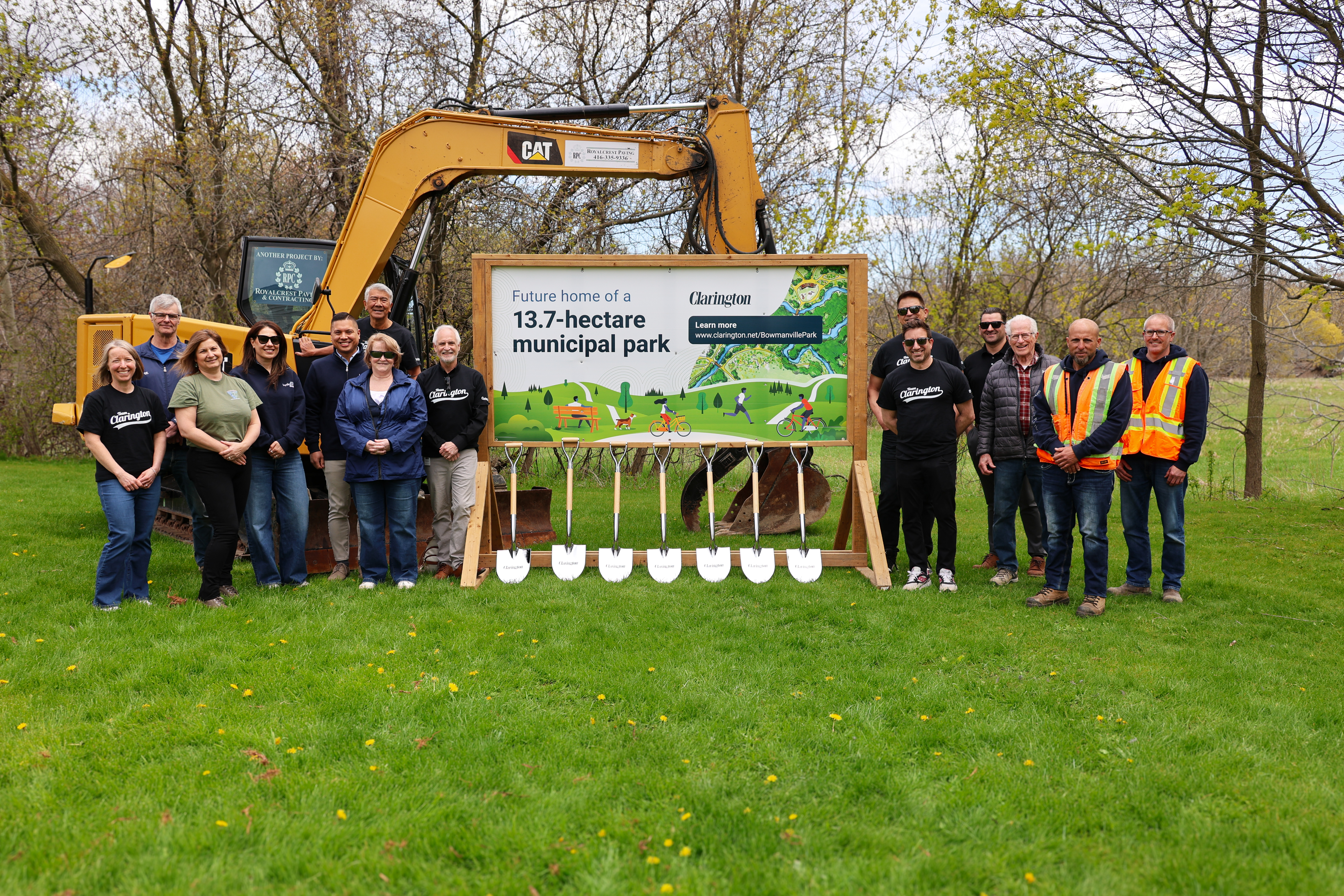 Clarington Council and staff, Hydro One representatives, members of Valleys 2000 and general contractors around a sign with the text future home of a 13.7 hectare municipal park. Yellow construction equipment in the background.