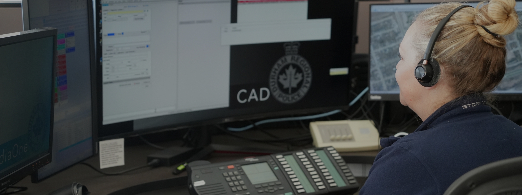911 operator on the phone in front of a computer