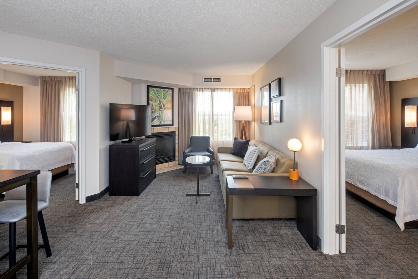 Hotel guest room with two bedrooms and living area with couch and TV