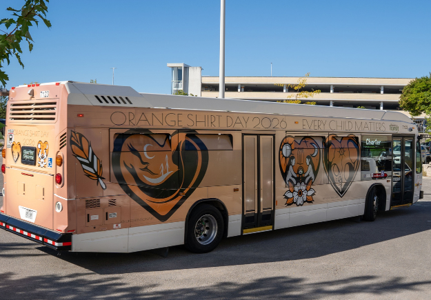 An image of a Durham Region Transit bus with an Orange Shirt Day wrap featuring artwork from various artists.