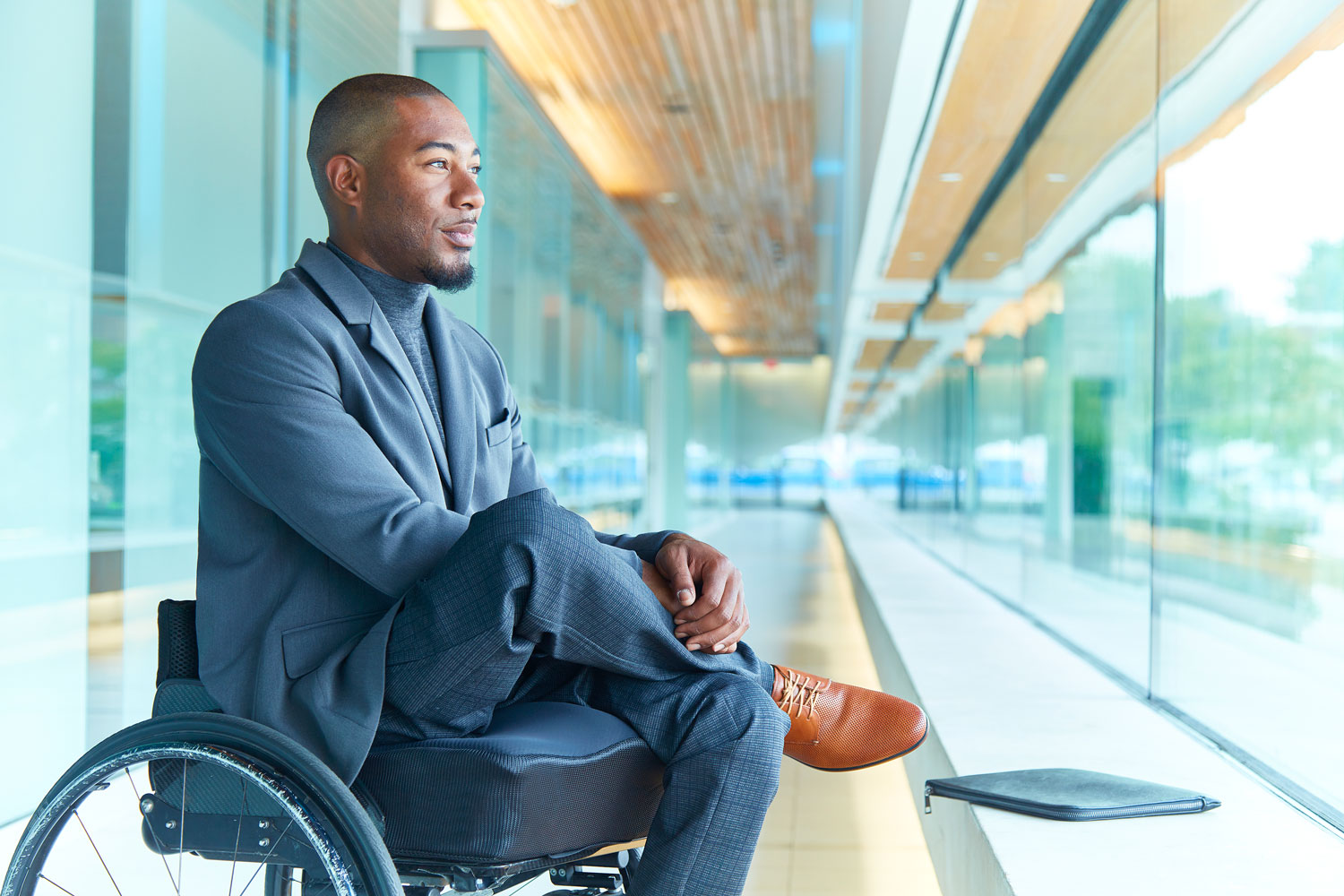 Anthony Lue looking out the window in a modern commercial building.