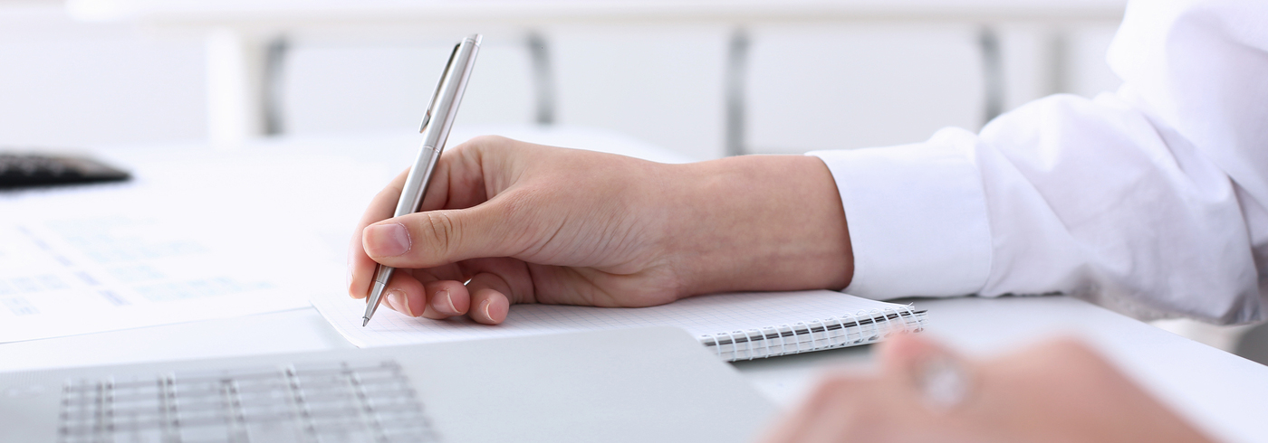 Individual sitting at a desk writing a report