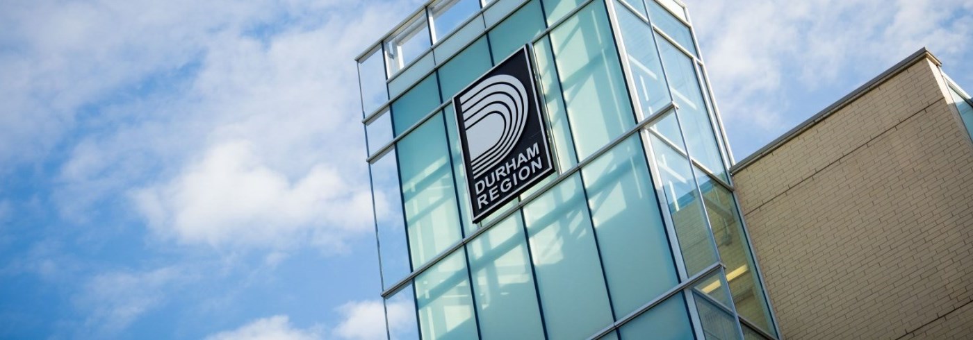 Glass building facade with Durham Region logo in white on a dark navy sign