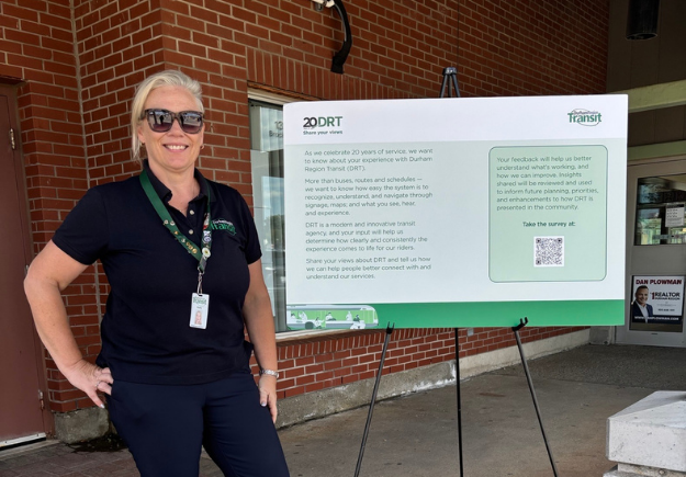 Holly Trotman smiling standing next to the 20 years of DRT sign.