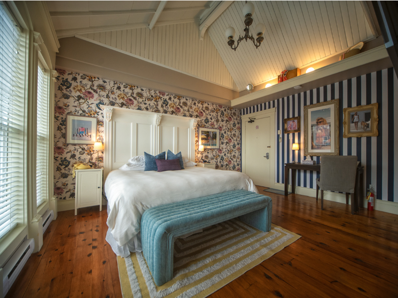Image of a hotel room at a boutique inn with colourful wallpaper and high ceilings