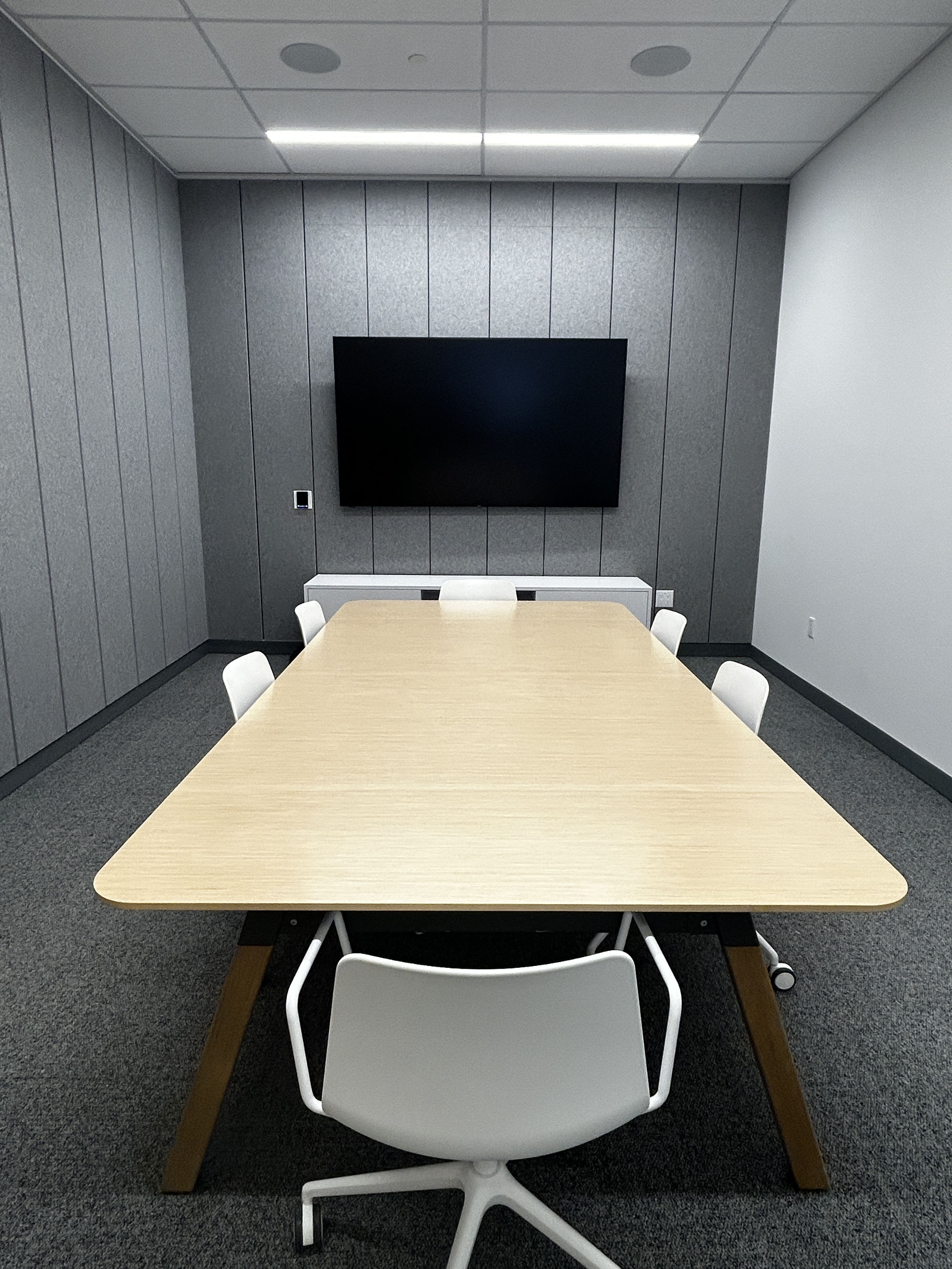 a meeting room with chairs around a table and a tv for presenting