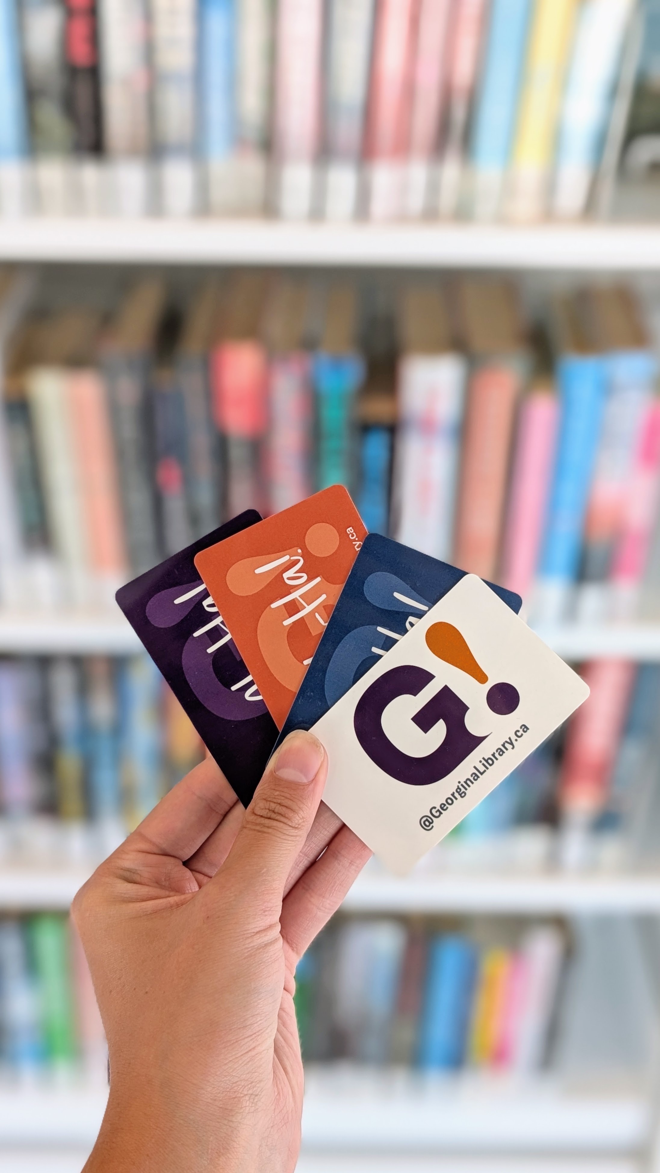 hand holding library cards in front of books