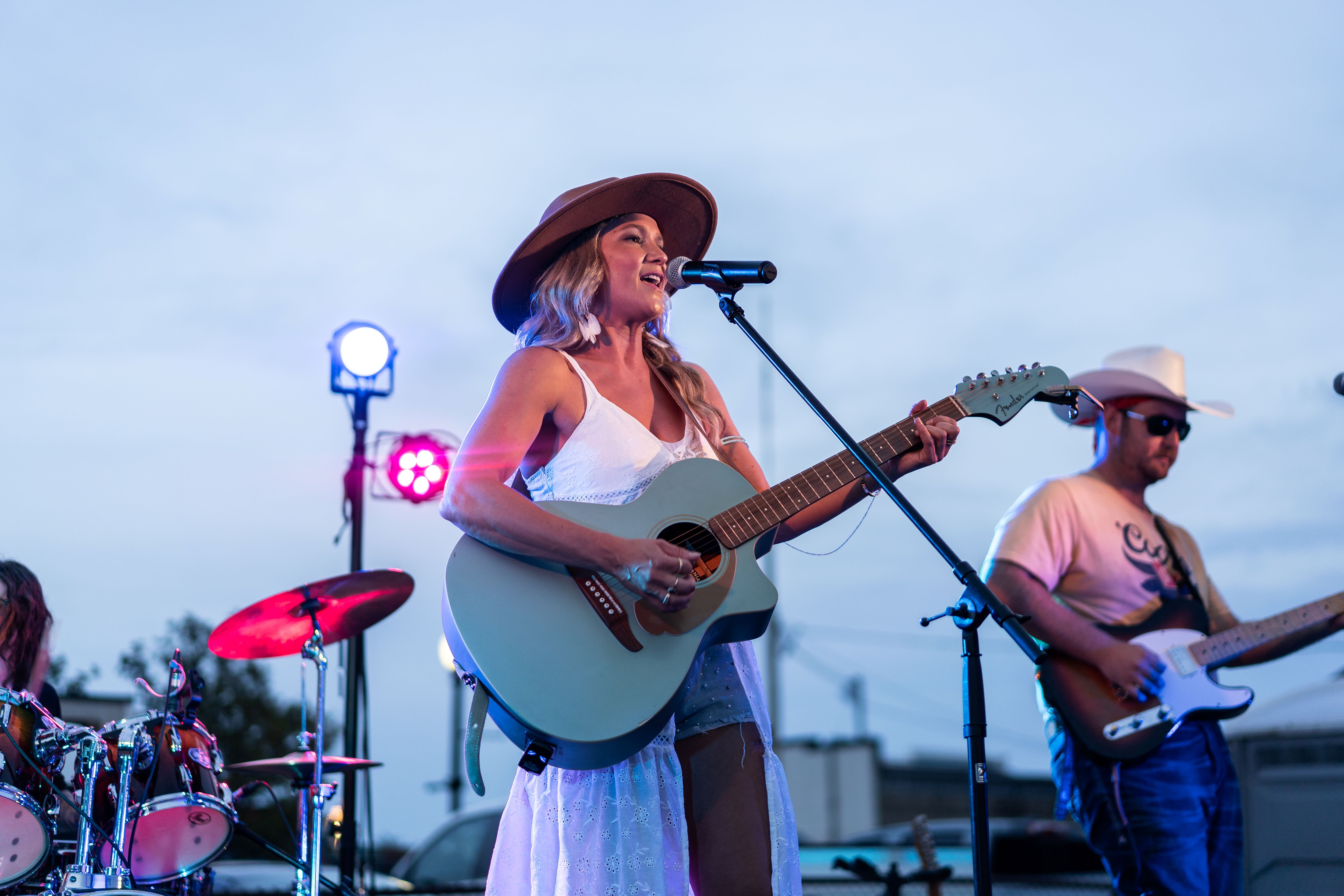 A woman sings and plays guitar on outdoor stage