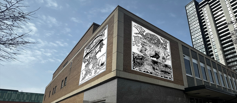 Outside corner of a building with a black and white mural on each wall