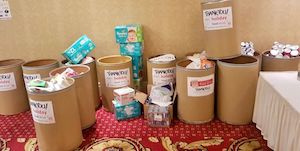 Collection bins labeled for donations are placed against a wall, filled with various items.
