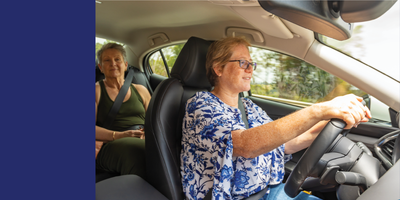 Woman driving with an older adult in back passenger seat