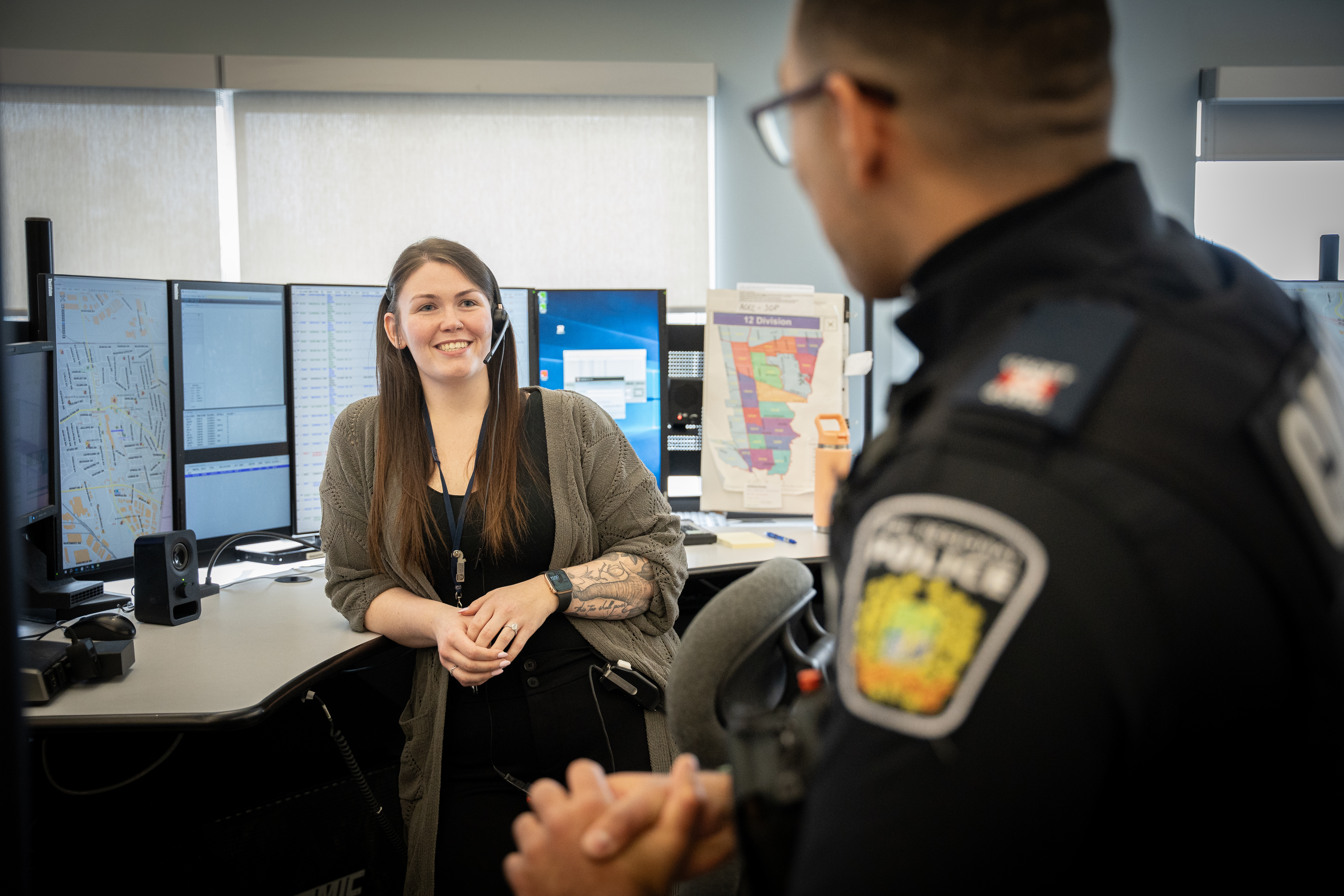 Police dispatcher smiling in front of computer