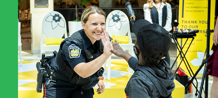 White female police officer smiling and high-fiving child