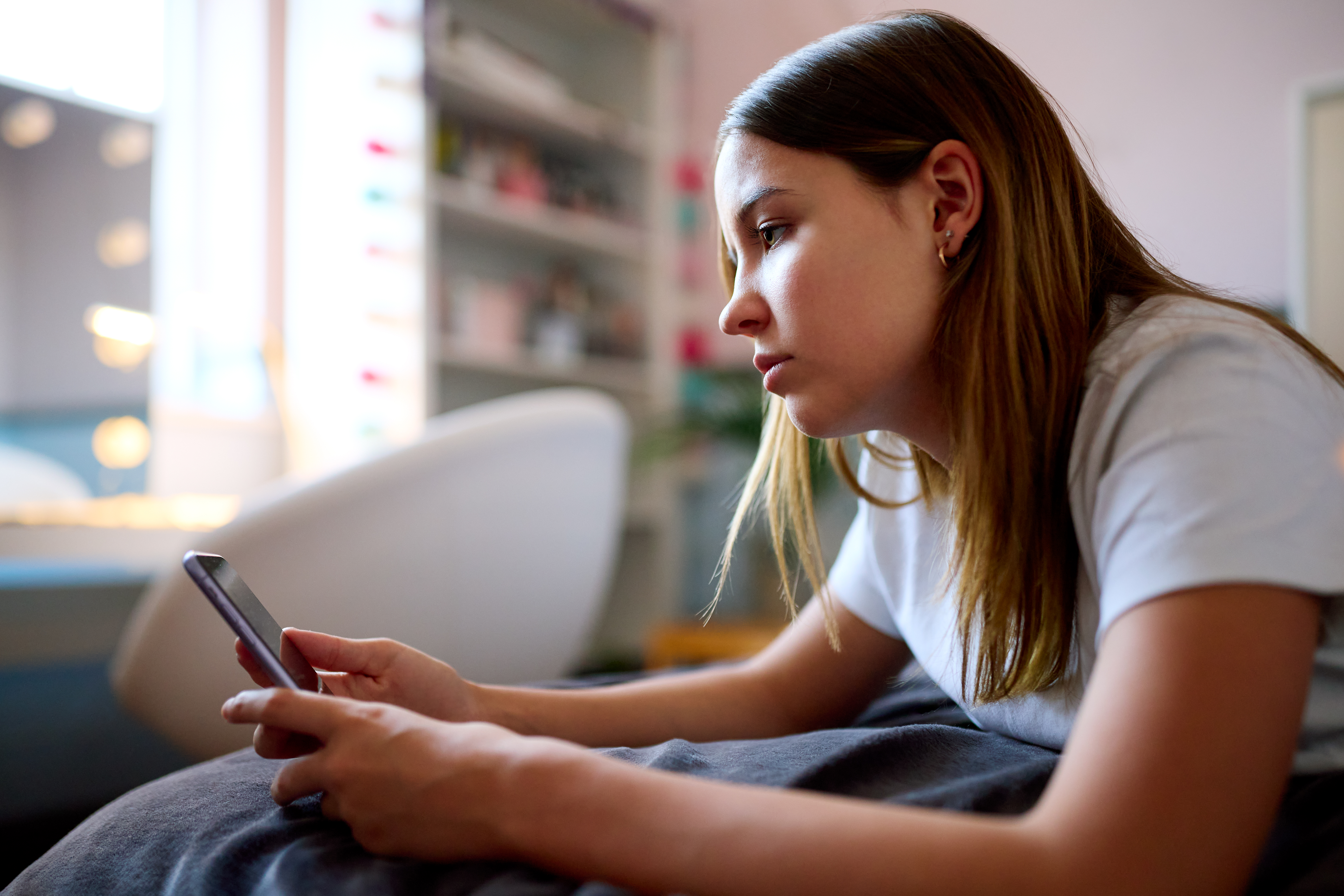 Teenage Girl Using Mobile Phone In Bedroom