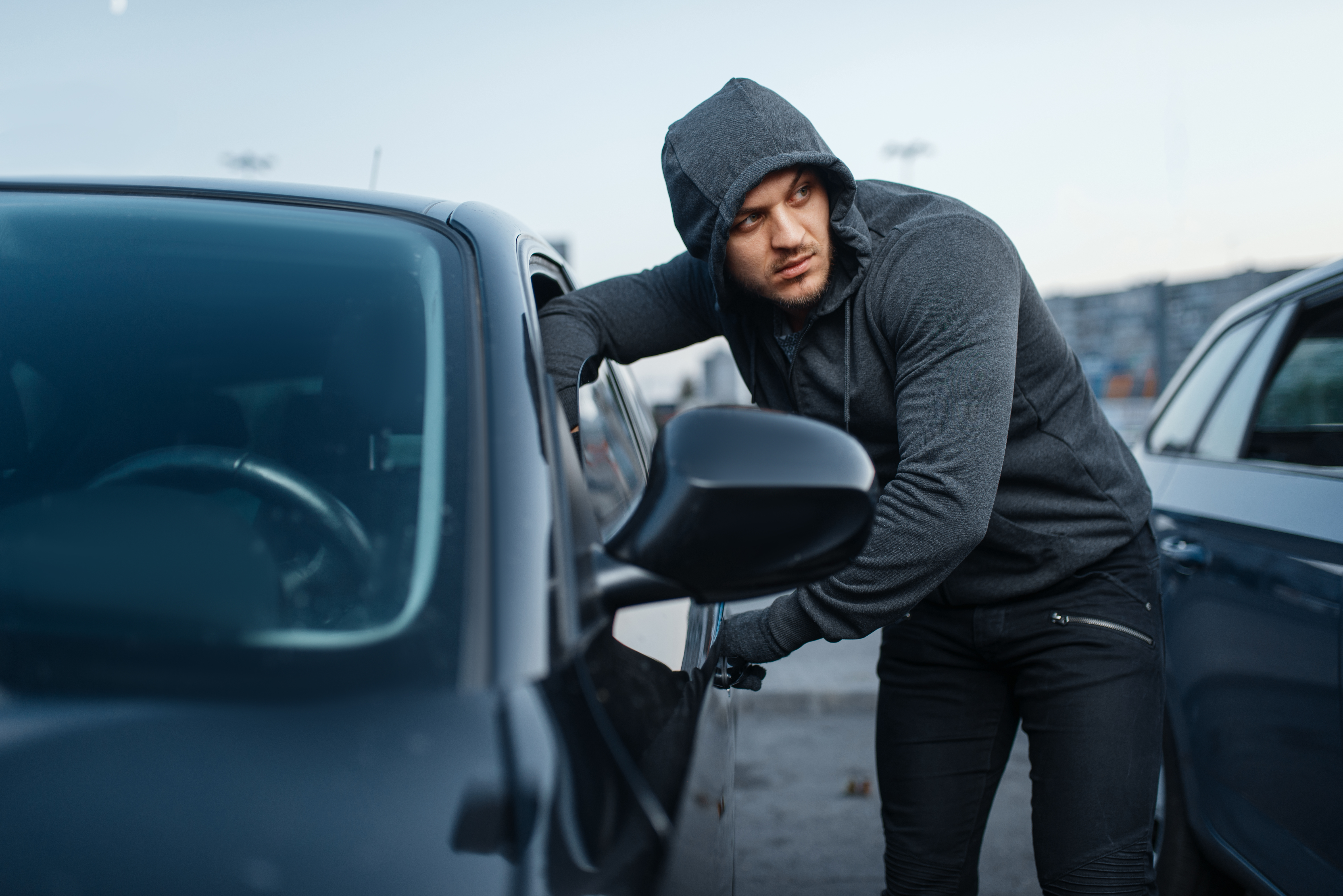 Hooded Man Near A Car In Urban Setting