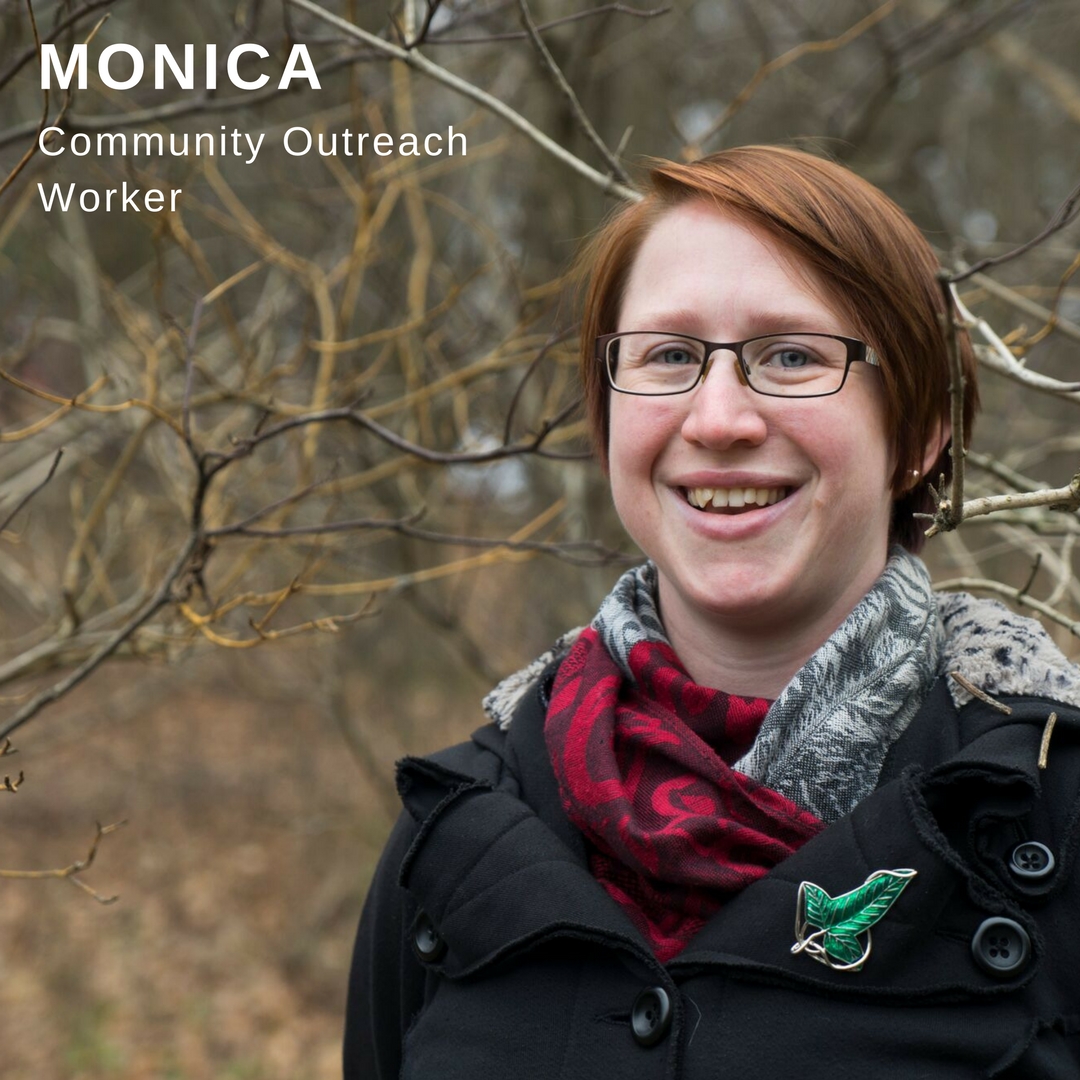 Young woman with red hair smiling in front of wooded area