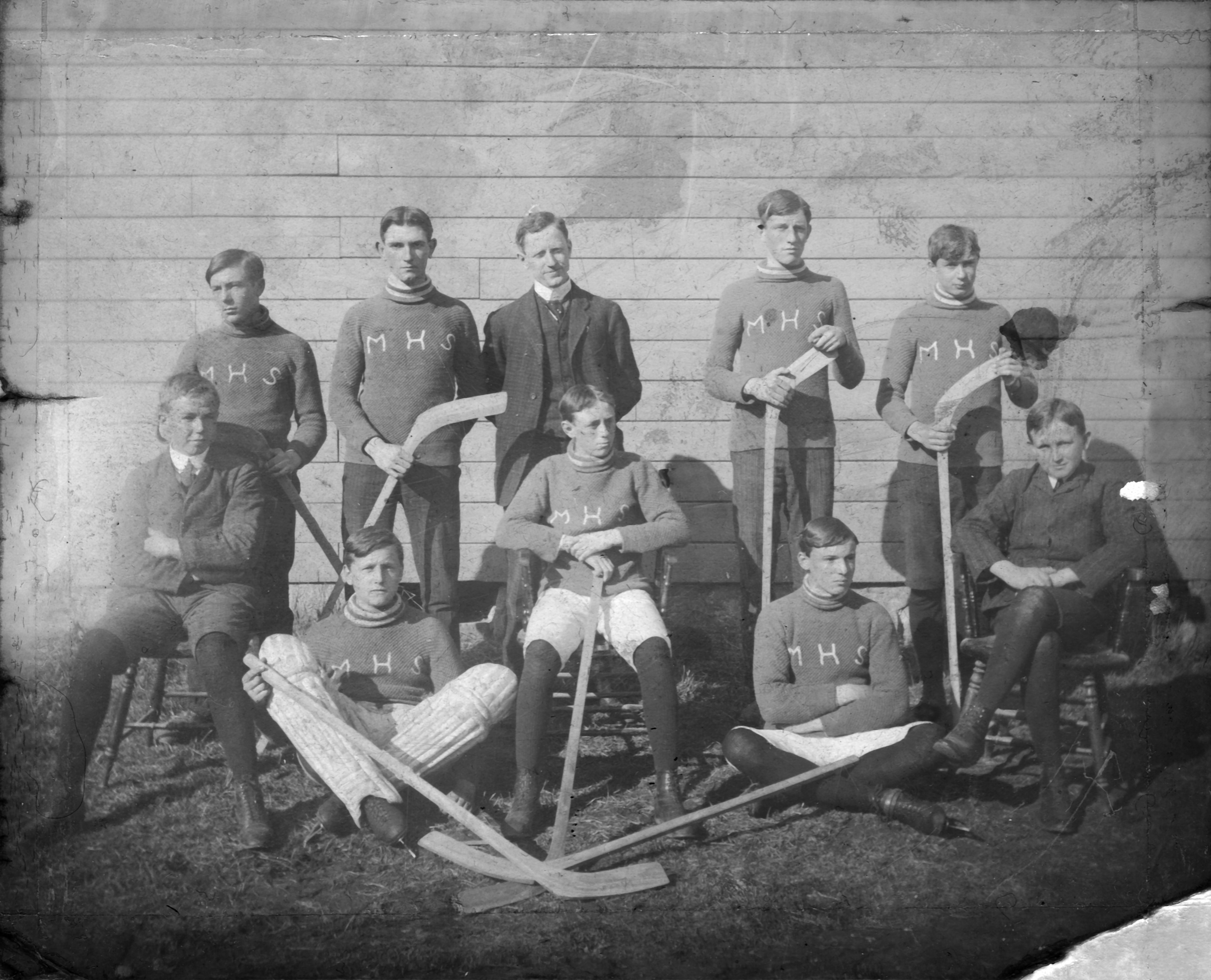 Mitchell High School hockey team posing in uniform with hockey sticks in their hands.