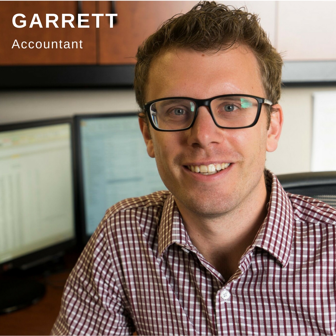 Man with glasses smiling in front of his computer