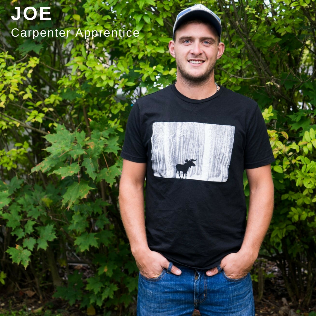 Young man smiling and standing in front of trees