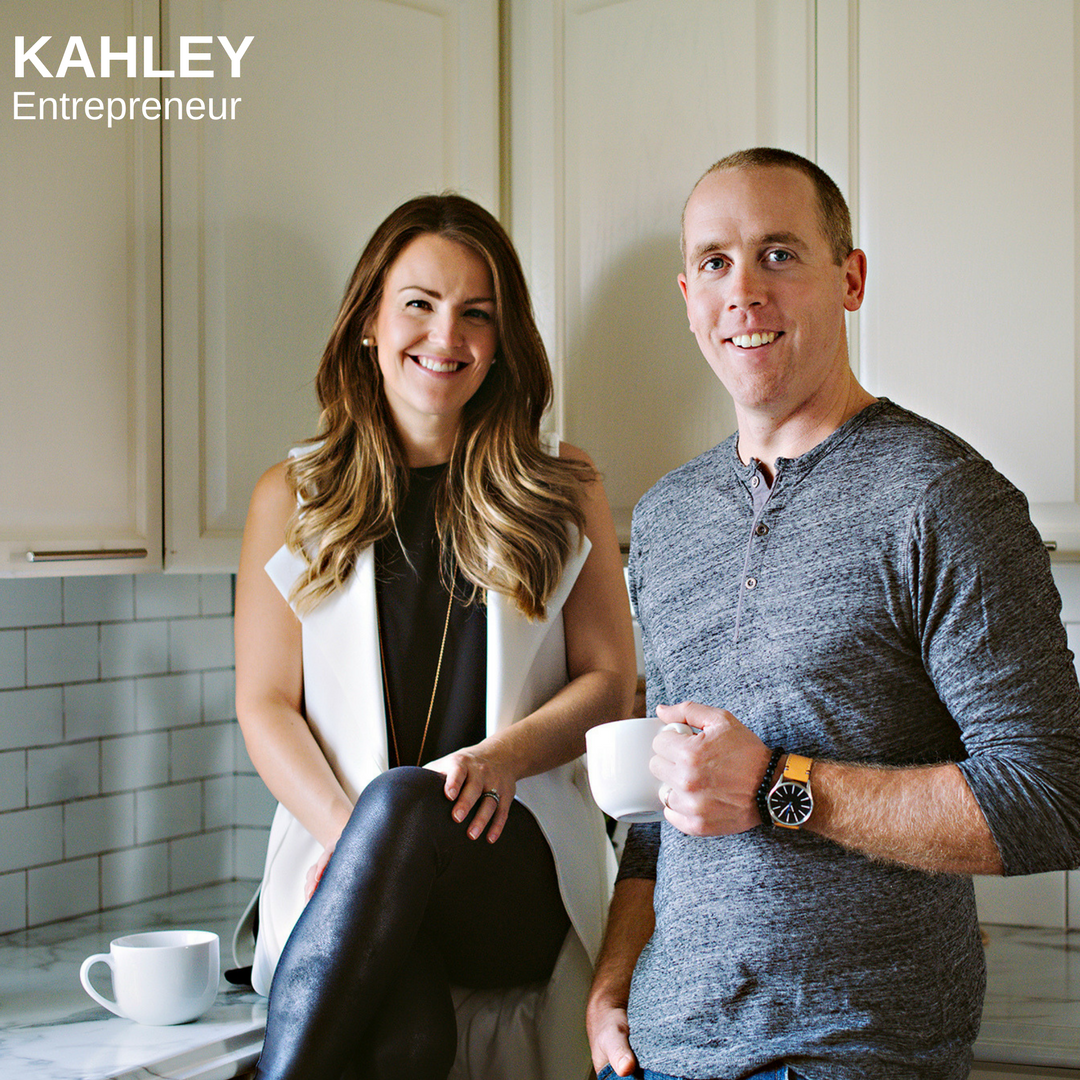 Man and woman in a kitchen smiling and drinking coffee
