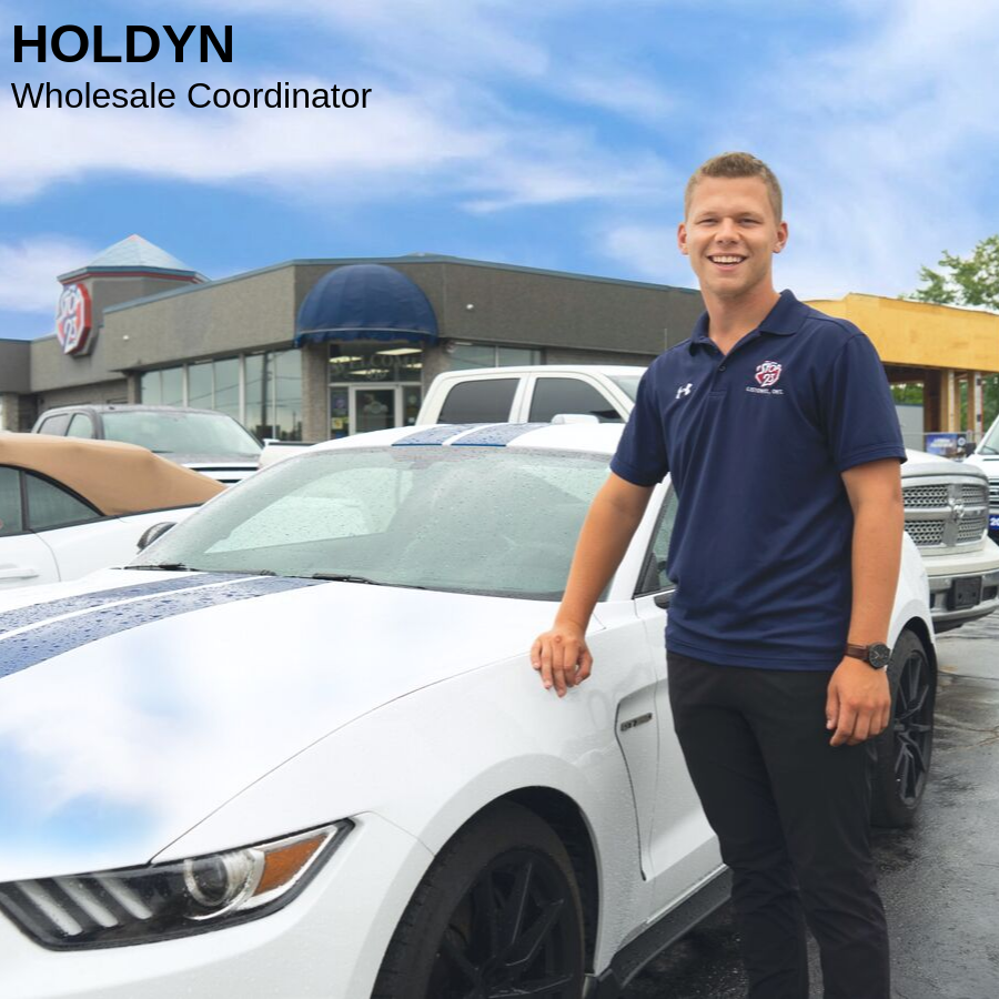 Blonde man standing beside a white car