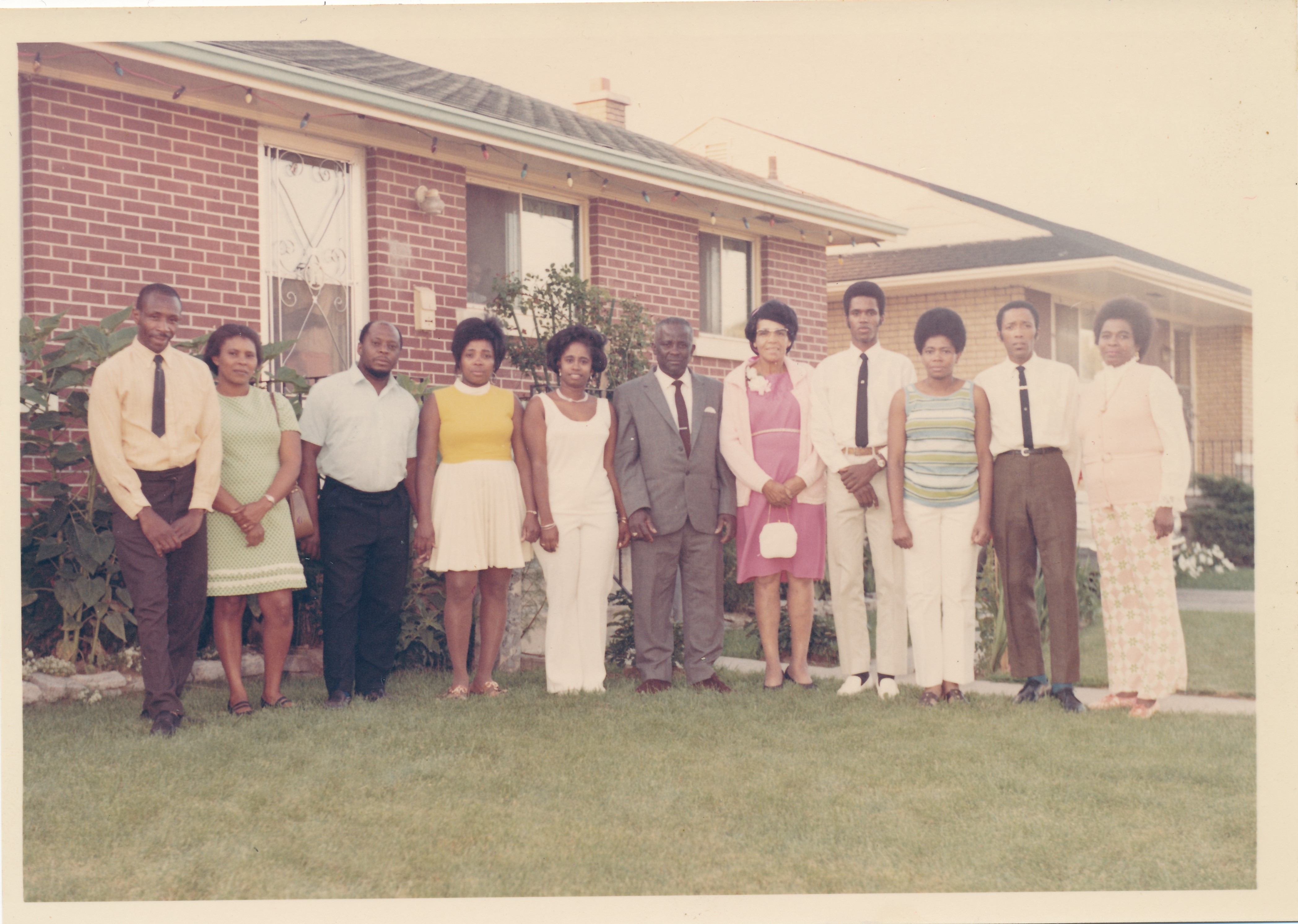 A group of black people standing on the lawn of a house.