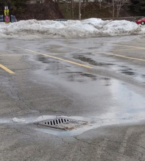 snow melt draining into catch basin in parking lot