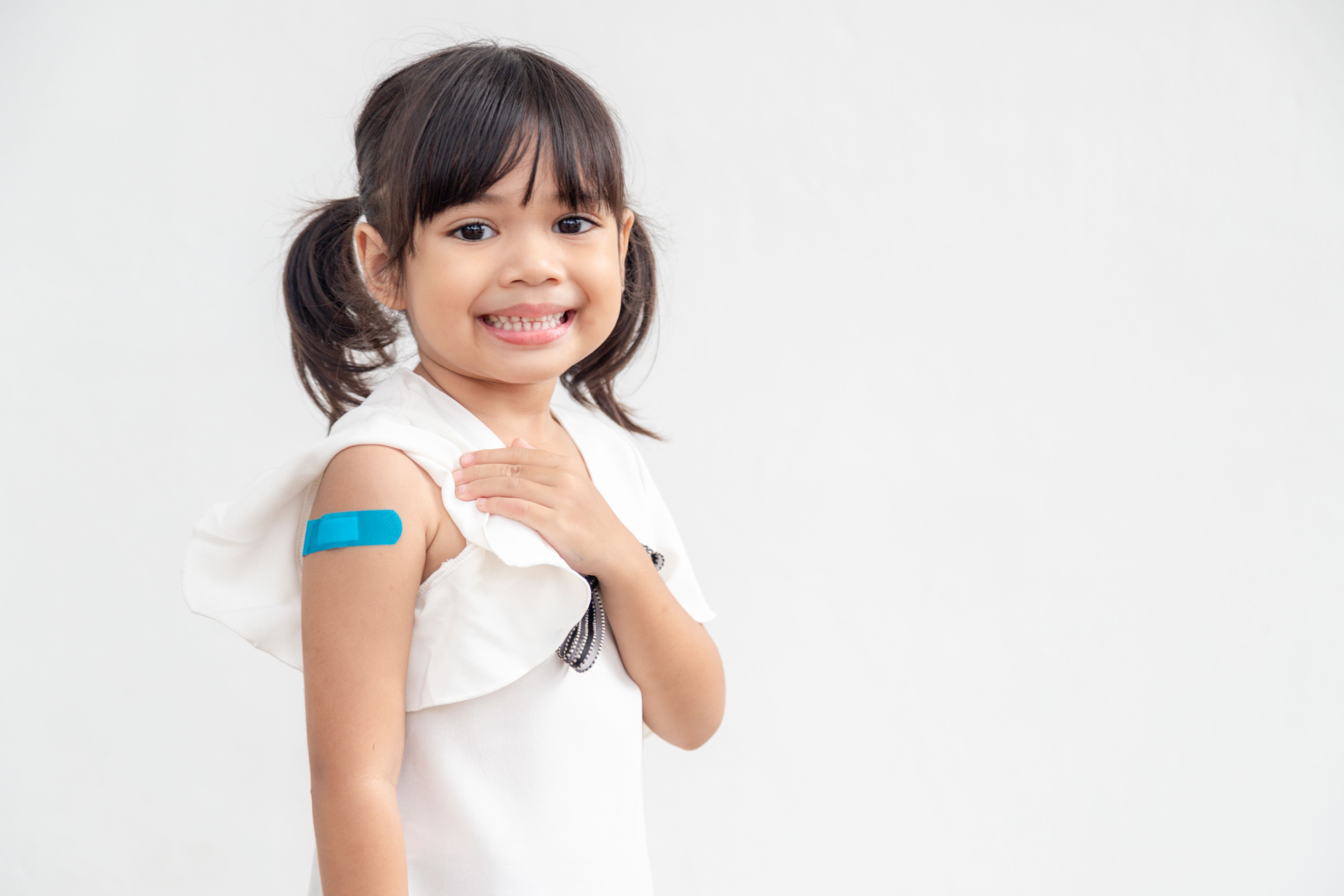 Smiling school aged child showing off a bandaid on her arm