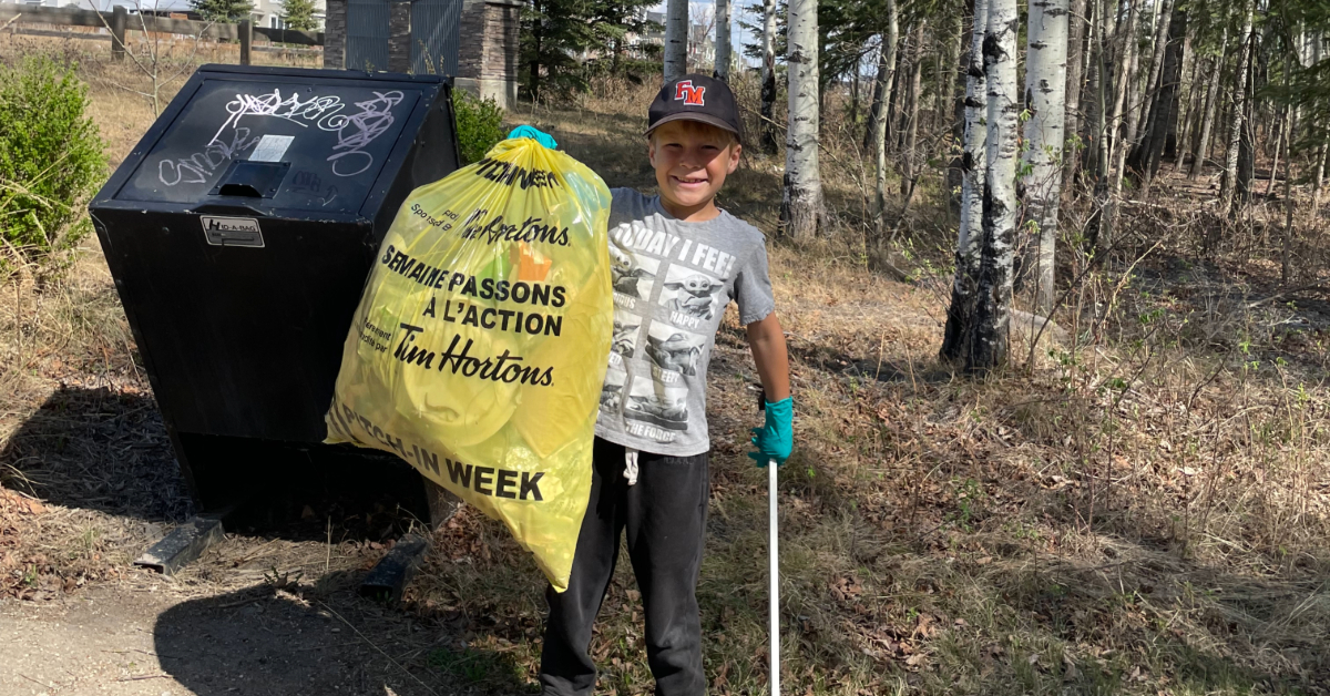 A Community Cleanup volunteer holds up a bag of litter collected along the trails.