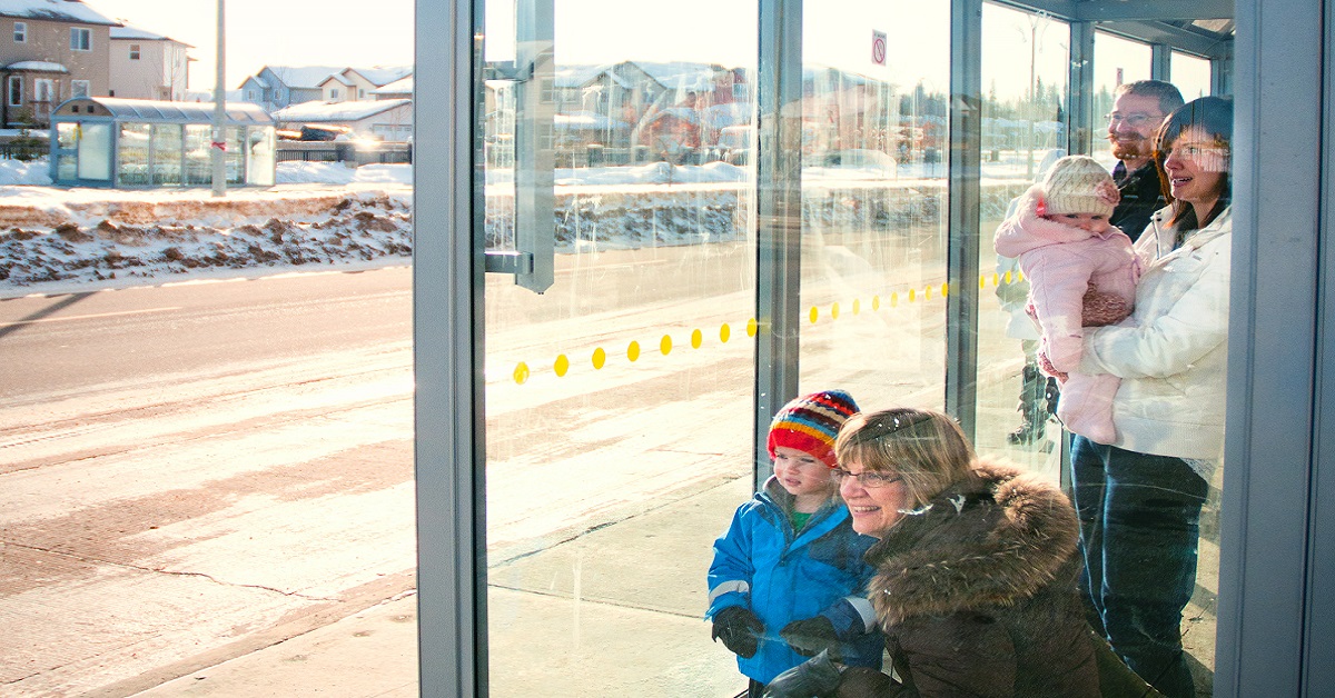 A family waits at a Transit bus stop.