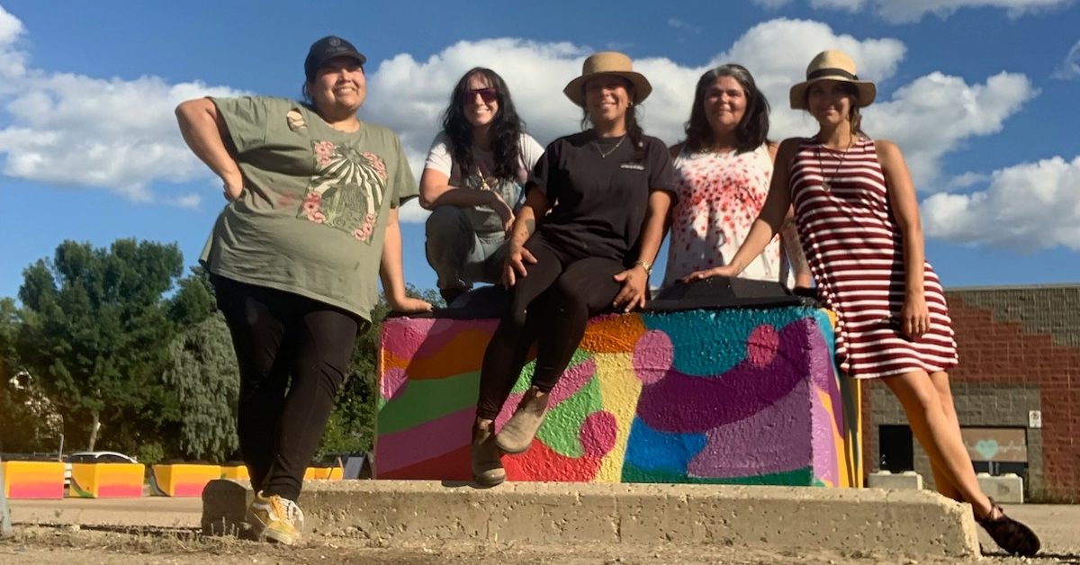 Haus of Bellefleur artist poses with mentees in front of a Mural Fest installation