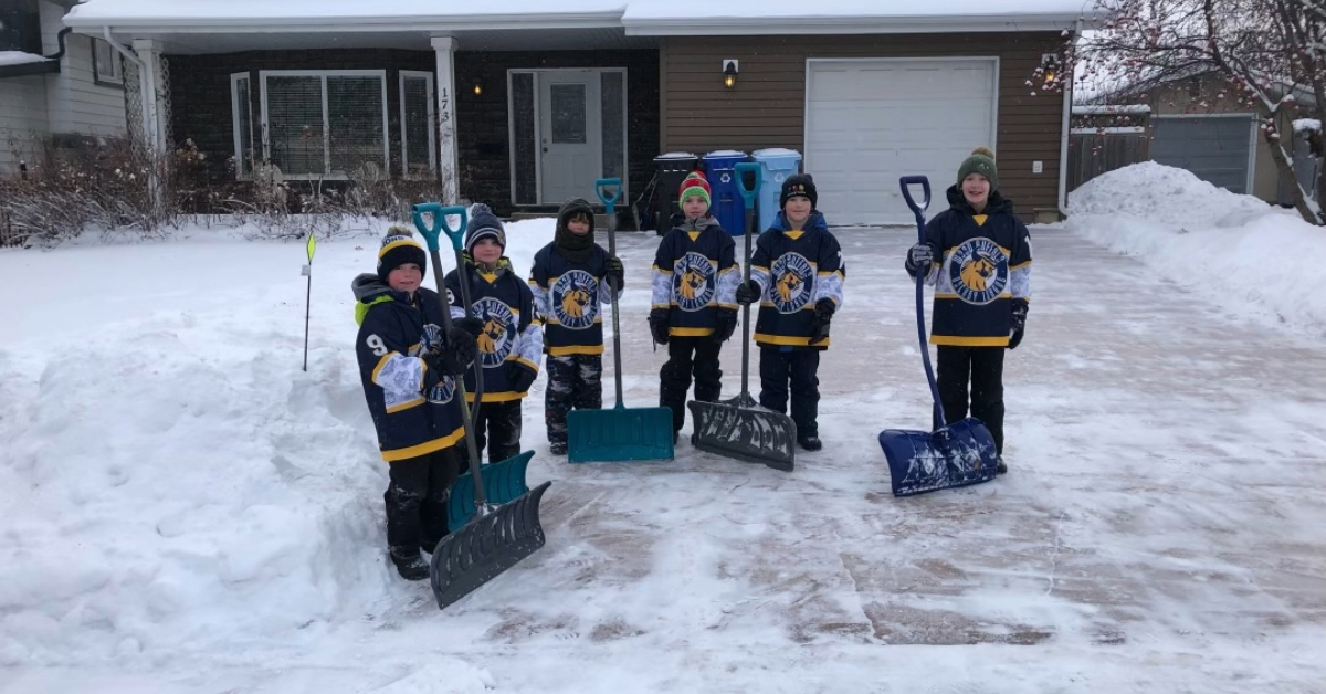 volunteers shoveling snow in a driveway