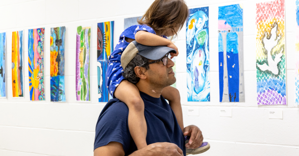 A parent and child view street banners at the gallery space in MIP