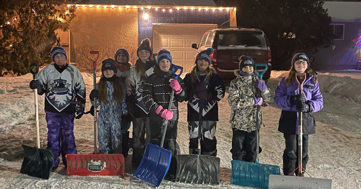 A group of Snow Angels pose after shoveling the driveway of a community member in need.