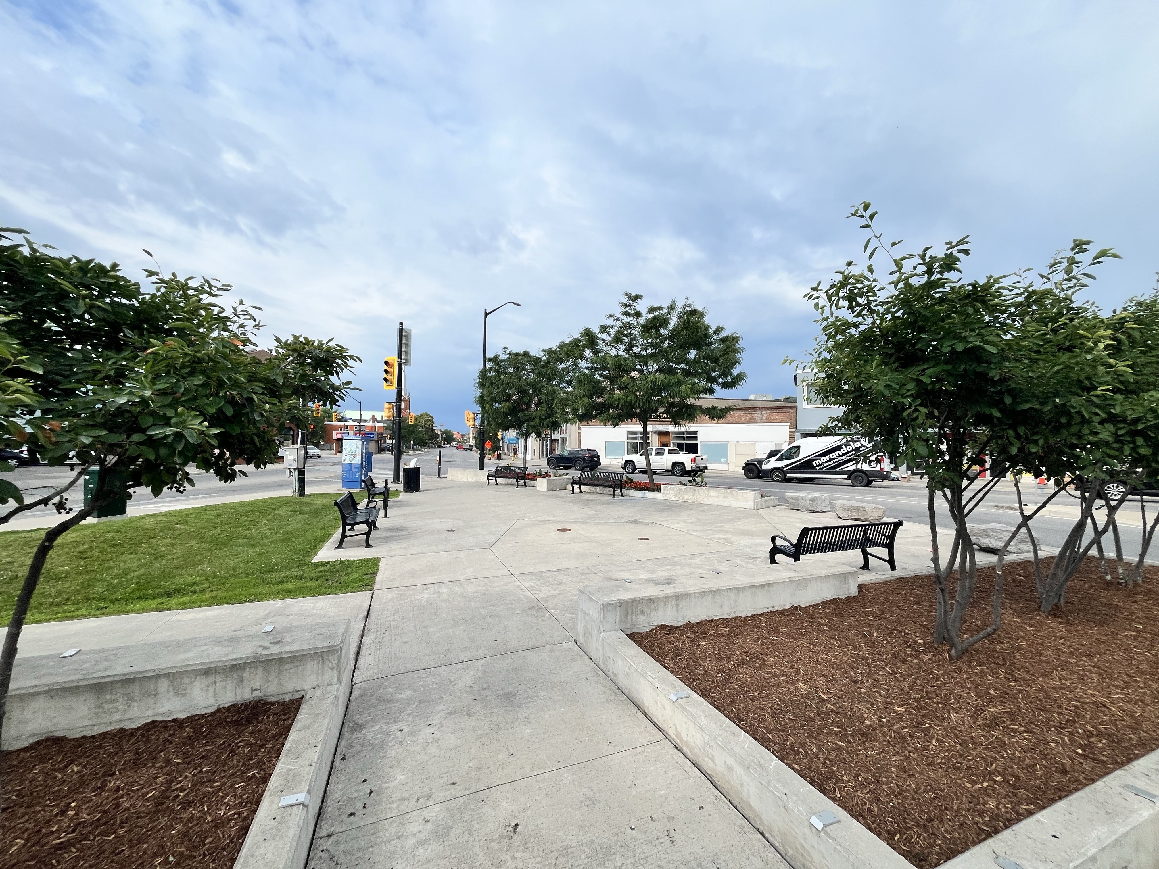 The Five Corners Parkette where Indigenous public art will be installed in the large concrete area surrounded by park benches, trees and grass.