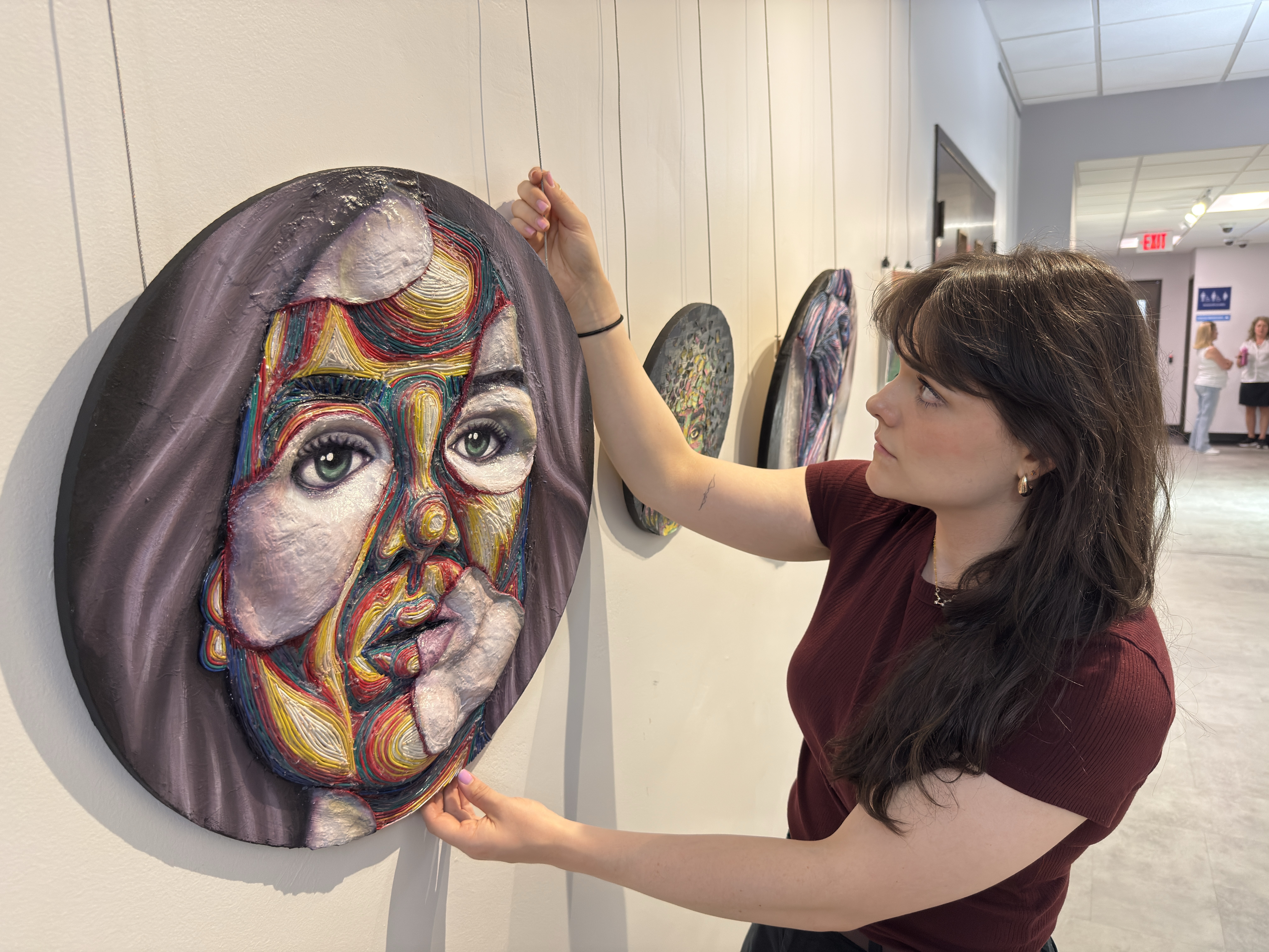 City Culture Coordinator Chelsea Ryan hangs a piece of art, part of the "Full Colour: A Celebration of 2SLGBTQIA+ Art and Expression" in the Third Floor Gallery space at City Hall.