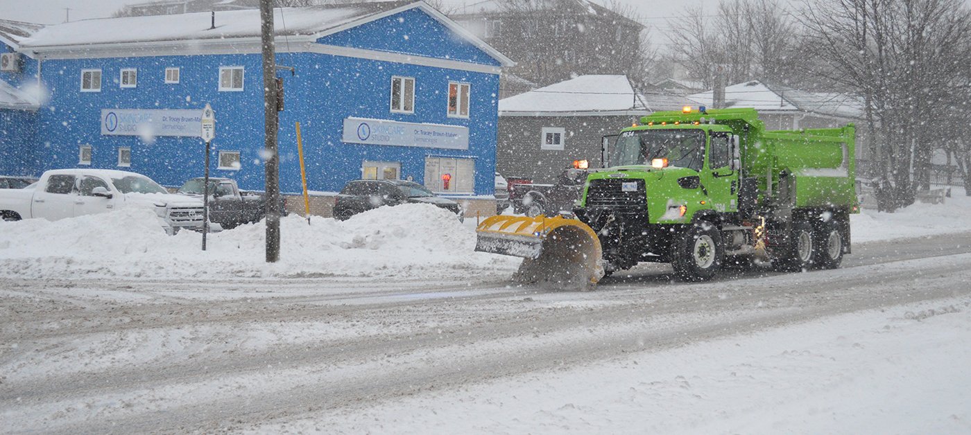 a city plow going down the street during a snowy day