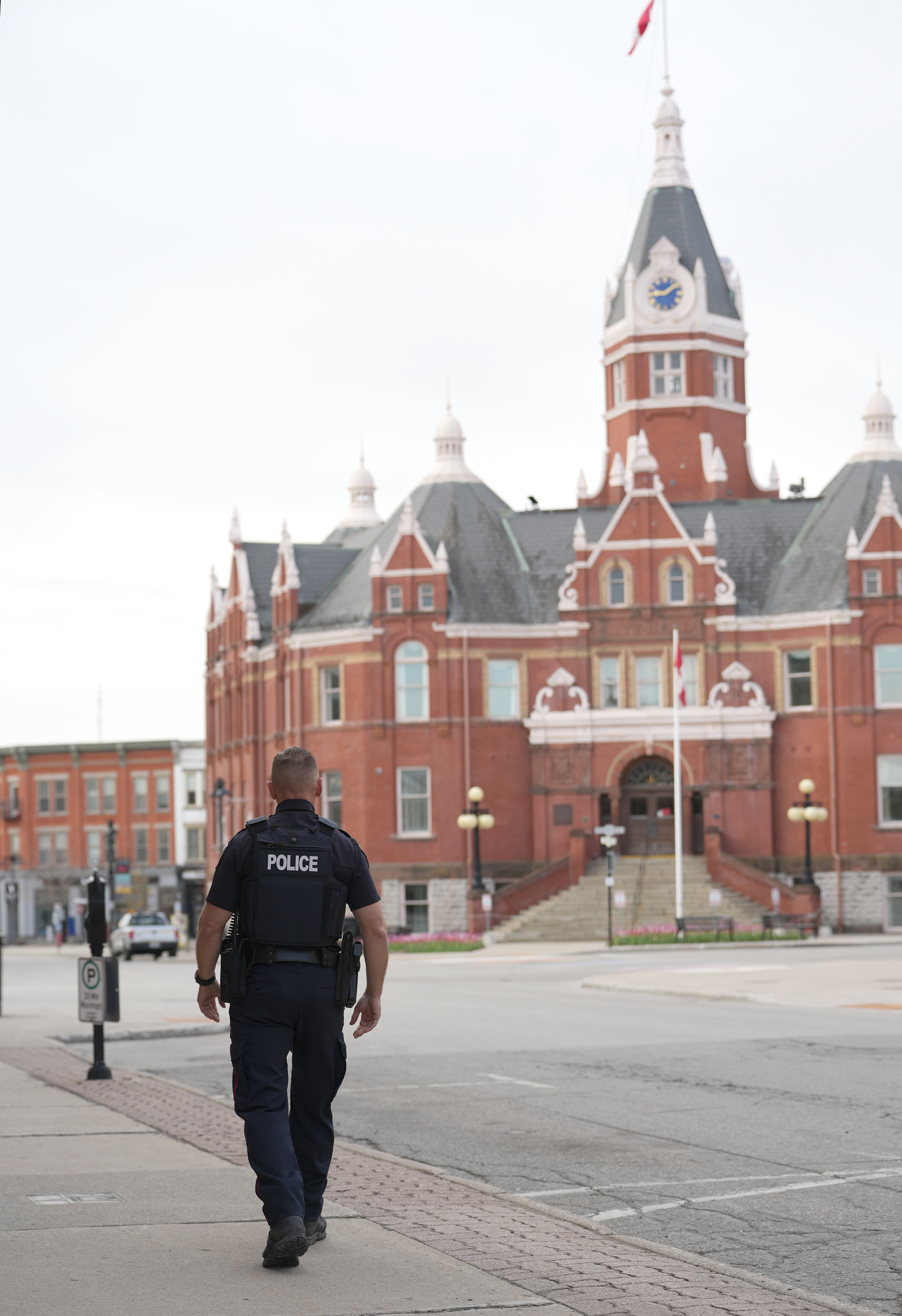 A police officer walking on a downtown street, with City Hall building in the background