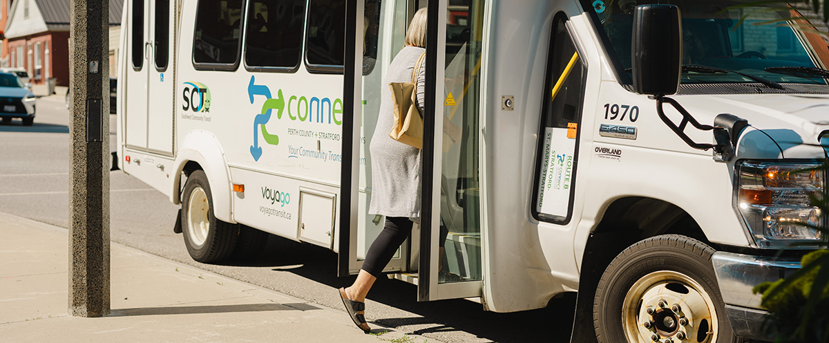 A person stepping onto a white bus, with PC Connect printed on the side