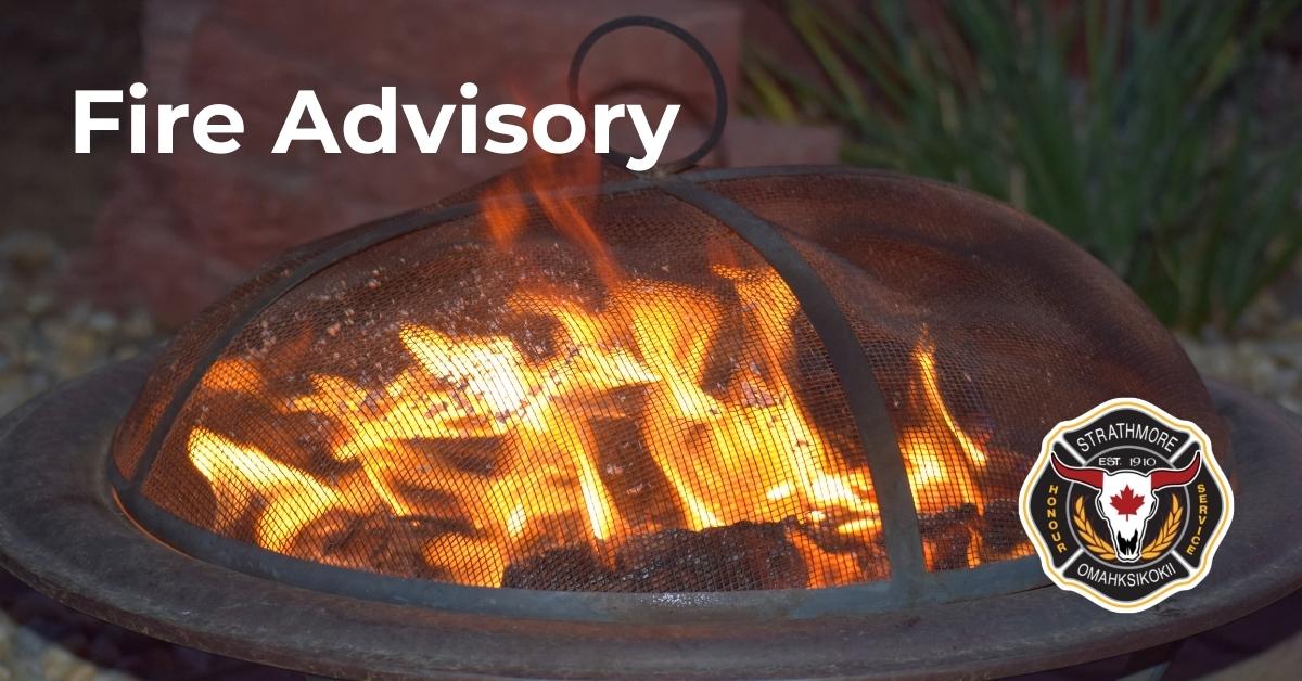Picture of a small outdoor fire pit with a fire burning in it. Text overlay: Fire Advisory.