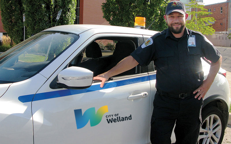 bylaw officer standing in front of a bylaw car