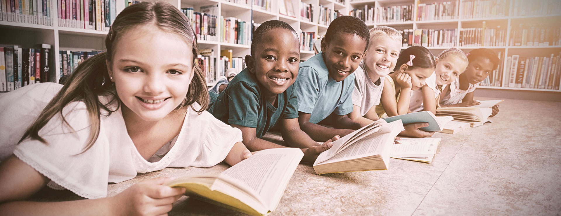 children holding books at a table in a library