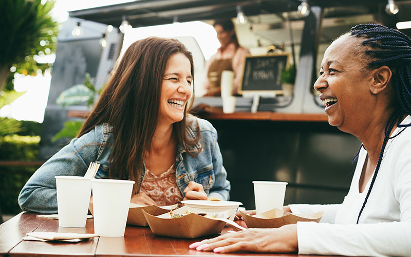 two women enjoying food from a food truck