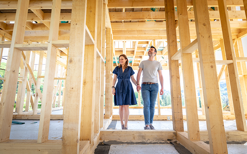 a couple holding hands walking through a home construction