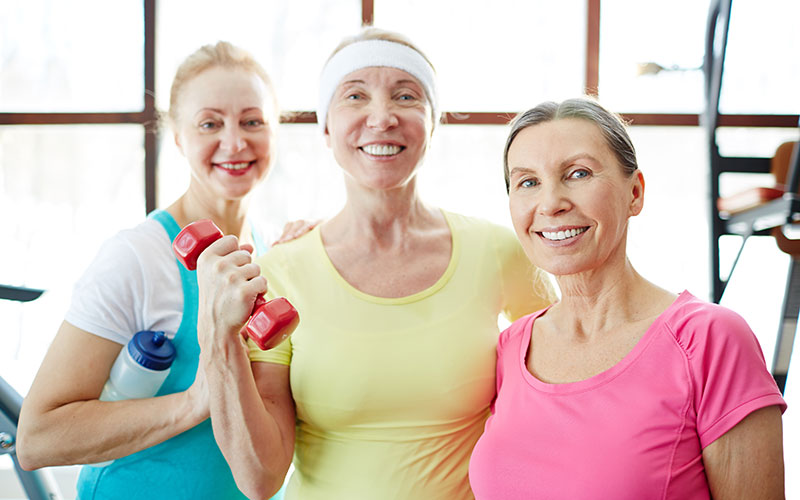 three women posing with hand weights