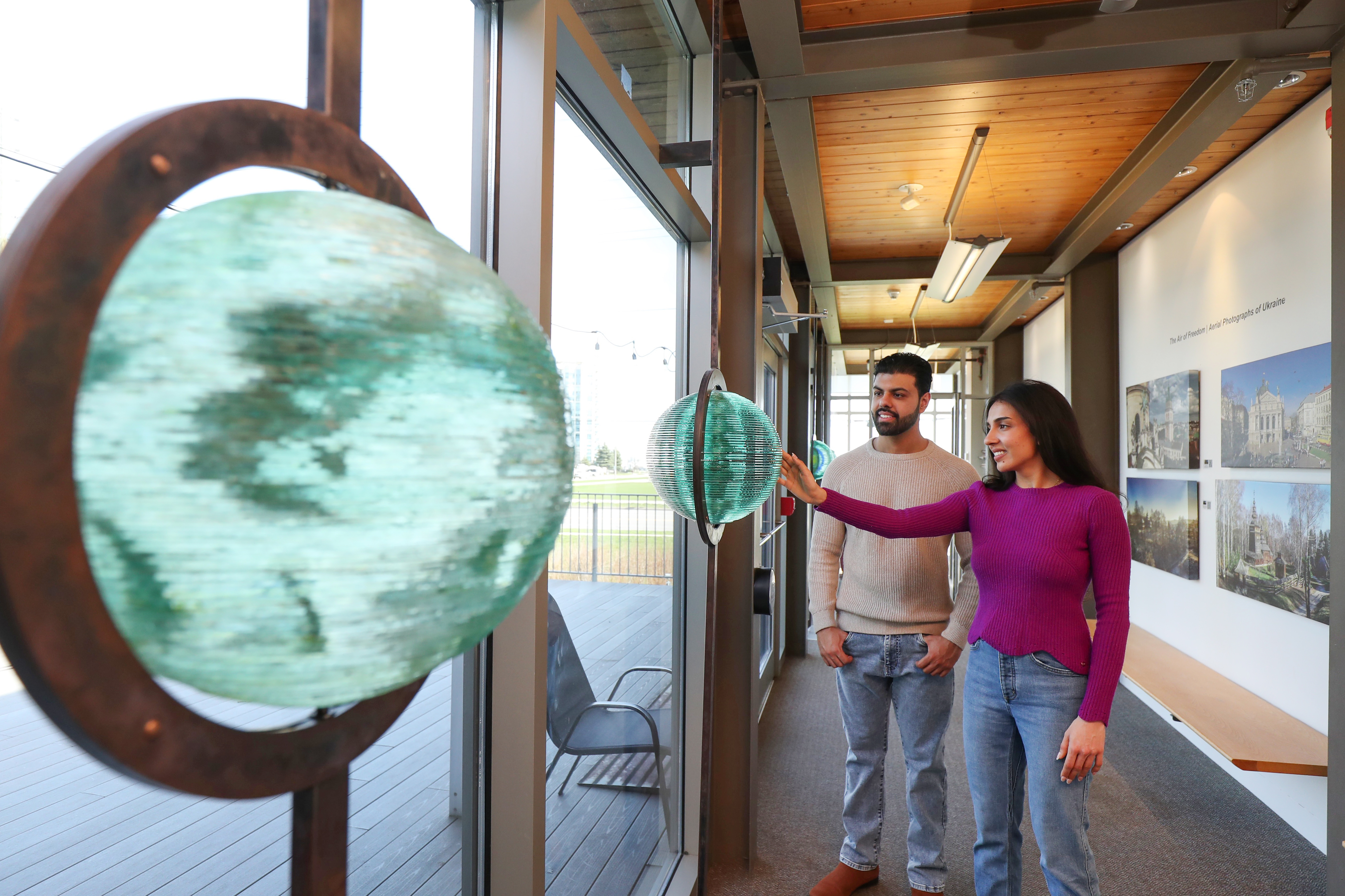Couple walking through station gallery staring at glass sculpture art 