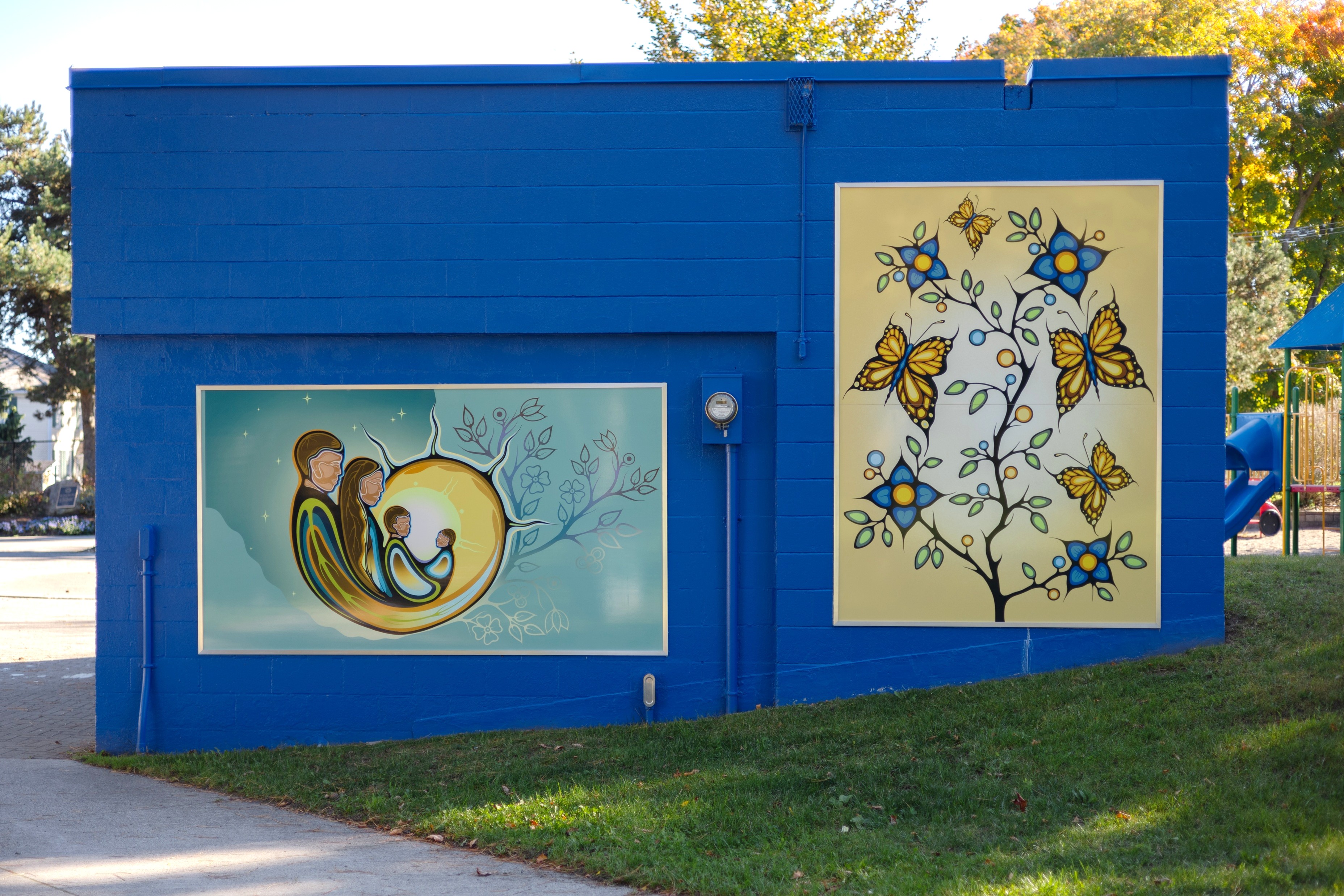 Photo of two mural panels on blue wall in park 