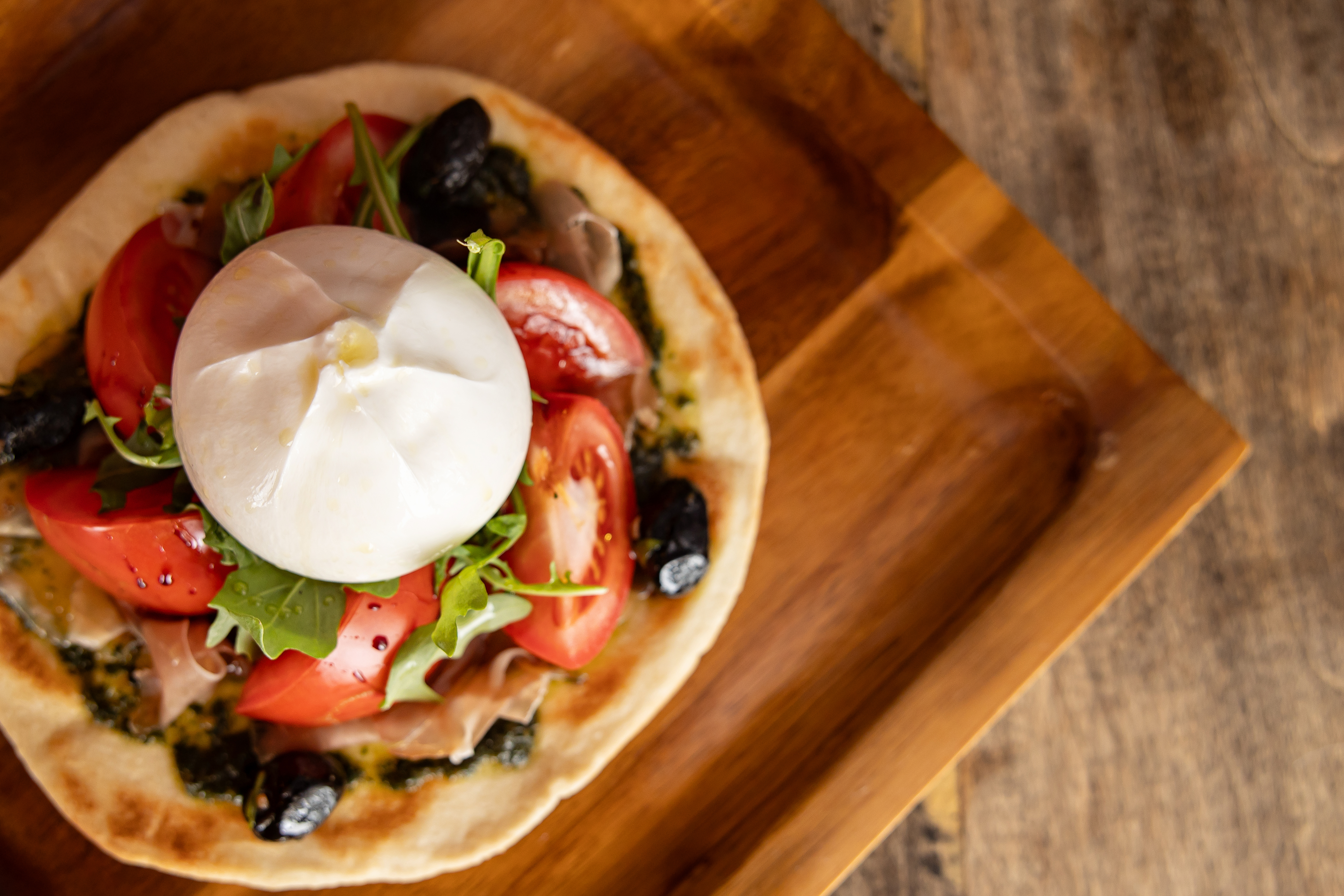 Flatbread on cutting board with fresh mozzarella on top 